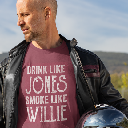 Man holding a motorcycle helmet wearing a Drink Like Jones, Smoke Like Willie t-shirt and leather jacket.