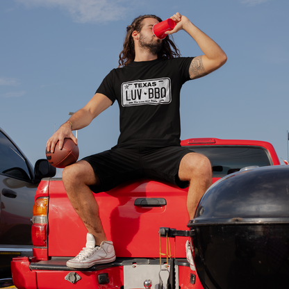 Man drinking a beer on a truck bed during summer wearing a Lone Star Roots t-shirt
